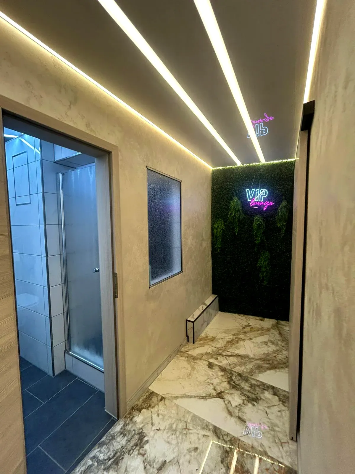 Flur mit Marmorboden, begrünter Wand und Neon-Schriftzug VIP Lounge