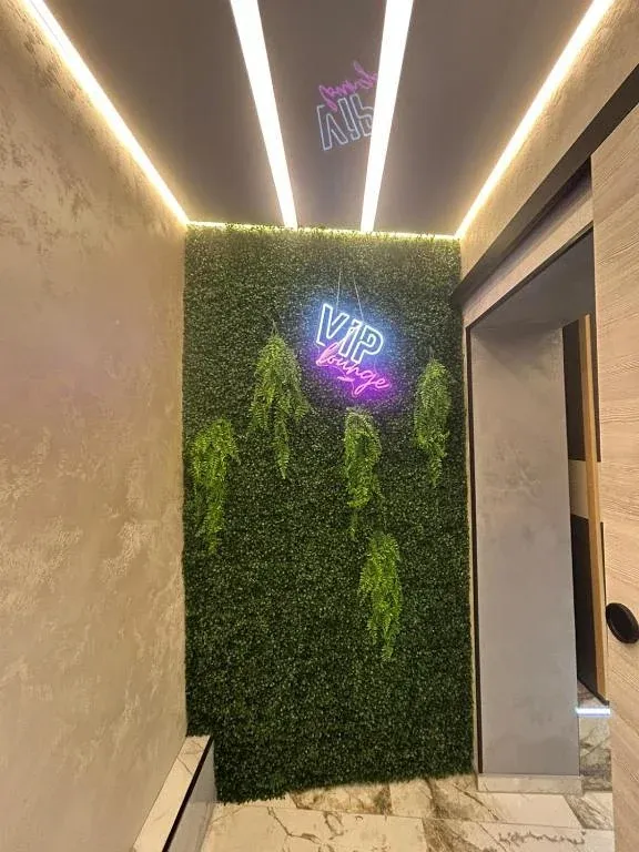 Begrünte Wand mit Neon-Schriftzug VIP Lounge im Eingangsbereich