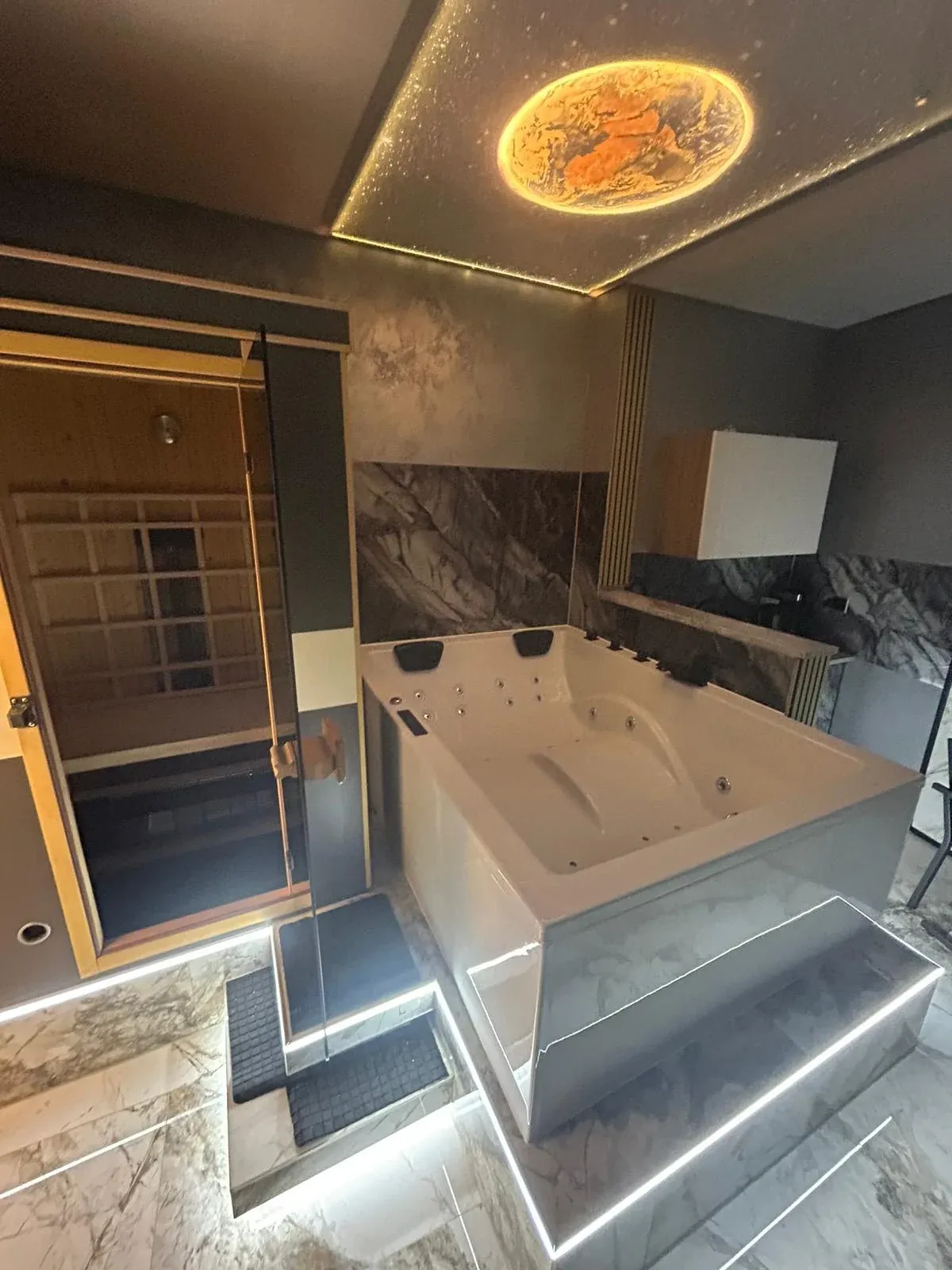 Private Sauna mit Glastür direkt neben dem Whirlpool, darüber die Planeten-Decke